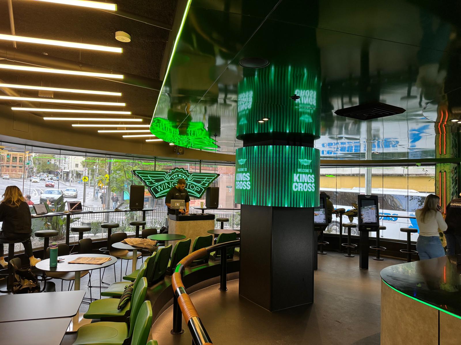 Wide venue view showing the central LED column display integrated with the surrounding hospitality environment.