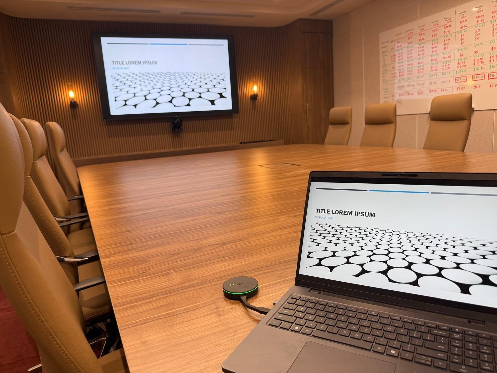Close-up of the boardroom's video conferencing touch panel and speakerphone puck on the meeting table.