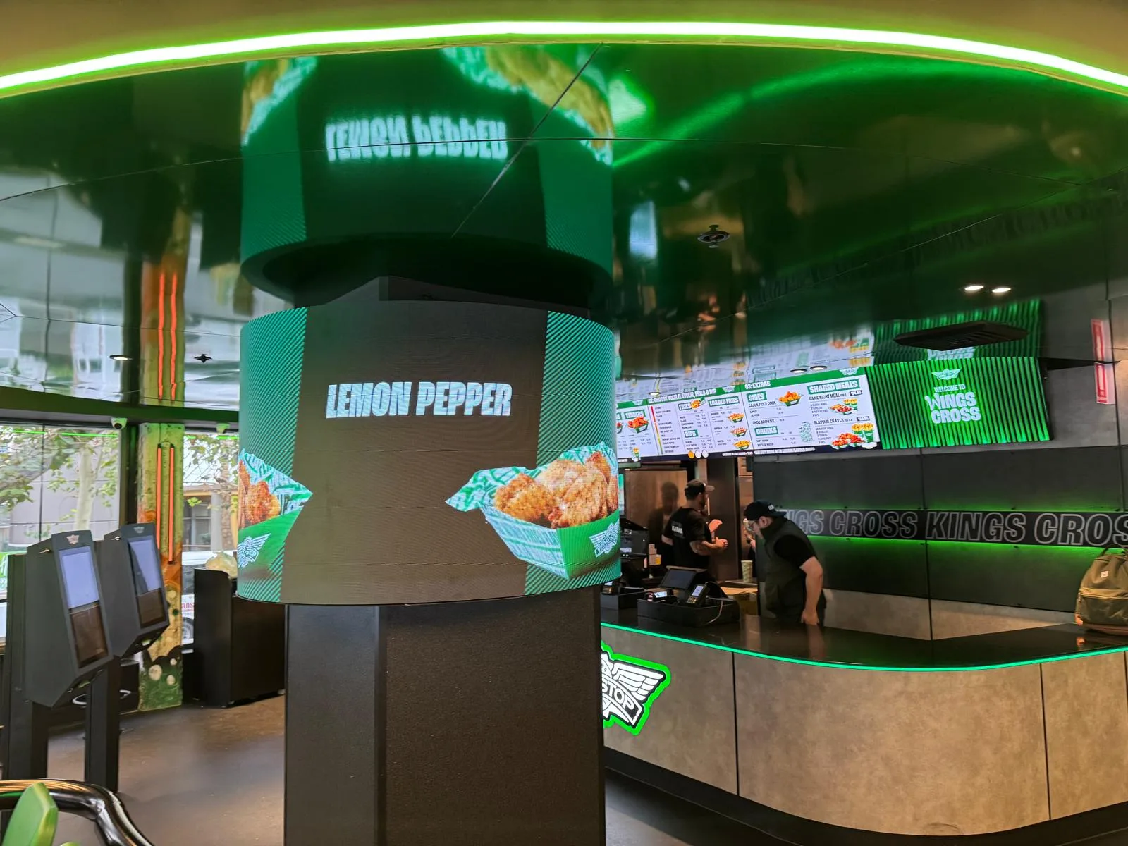 A finished curved LED column installation at a Wingstop store, displaying branded rotating menu content beside the servery counter.